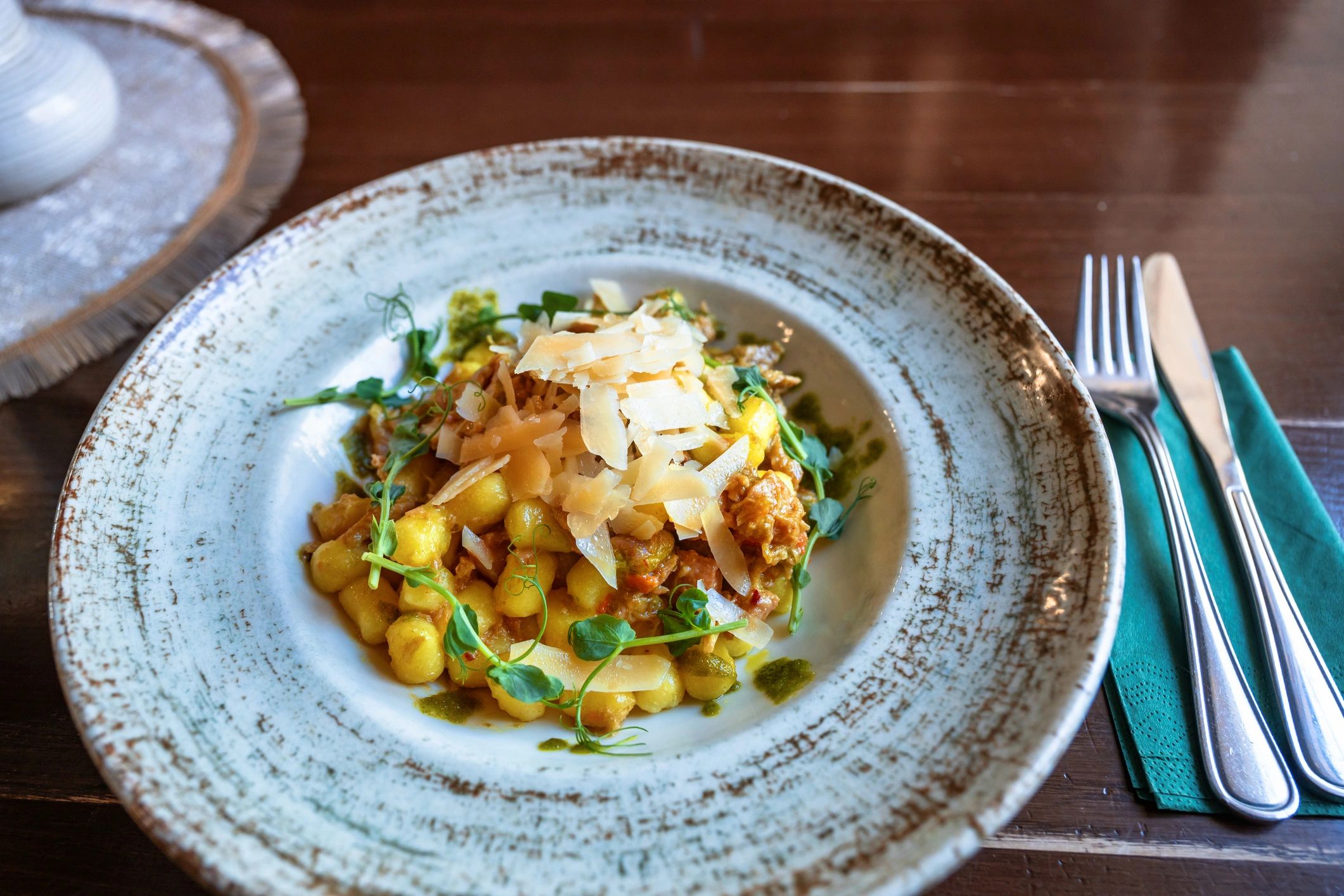 Gnocchi with turkey saute, pesto and grated parmesan on plate.